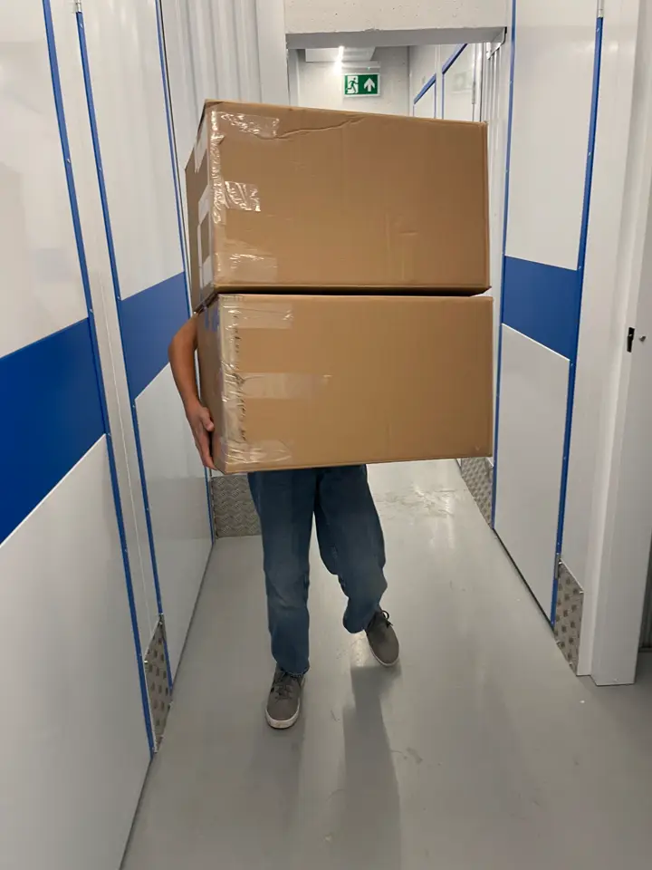 Client portant des cartons de déménagement dans le couloir des caves Mister Boxy à Kirchberg